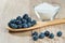 Wooden spoon with blueberries and glass bowl with sugar