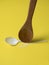 Wooden spoon breaks a plastic disposable spoon on a yellow background.