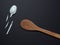 wooden spoon and a broken disposable spoon from a platik on a black background. superiority of natural materials.