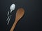 wooden spoon and a broken disposable spoon from a platik on a black background. superiority of natural materials.