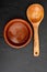 Wooden spoon and clay plate on black slate background with texture. Space to insert your text here. Letter for restaurants. Food