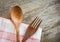 Wooden spoon and fork kitchenware set on napery on dining table