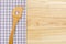 Wooden spoon on a purple checkered table cloth on a wooden background