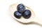 A wooden spoon with three ripe blueberries on the table. Fresh ripe juicy bilberries.