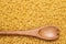 Wooden spoon on uncooked macaroni background