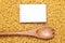 Wooden spoon on uncooked macaroni and notebook