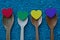 Wooden spoons with colored hearts on blue small stones