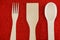 Wooden spoons, fork and spatula on a red background. View from above