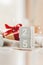 Wooden square calendar cubes with the date December 25 on beige cozy crumpled blanket, gift with red ribbon and sparkling garland