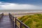 Wooden staircase leading into stormy sky and sea at De Haan, Belgium