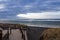 A wooden staircase leads to a black volcanic sand beach on the shores of the Atlantic Ocean