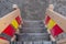 Wooden staircase on playground with plank steps covered with gray sand and red and yellow railings. Top view.