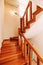 Wooden staircase with railings in a house with white walls, window and air conditioning.