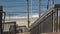 Wooden stairs, beach access in California USA. Coastal stairway, pacific ocean waves and palm trees.