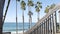 Wooden stairs, beach access in California USA. Coastal stairway, pacific ocean waves and palm trees.