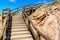 Wooden stairs with handrails leading up a rock