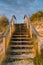 Wooden stairs leading over sand dunes to the beach at sunset with reeds and grasses