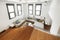 Wooden stairs of a loft apartment with four long windows, glass railing and fabric sofas with wooden floors