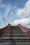 Wooden stairway with red banister in the blue sky