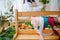 A wooden stand with colorful ribbons and twine on a florist's table littered with flowers