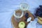 Wooden stand with two glasses of champagne and bottle, grapes and camembert cheese on white blanket in field. picnic.