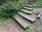 Wooden steps along the ground. An old ladder on a slide in the garden. Log path on the hill