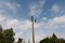 Wooden street lamp post with electric wires against blue sky with white clouds