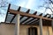 Wooden structure of the pergola supported by smooth cylindrical white columns shelter of a gazebo pergola. roof lined with glass.