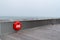 A Wooden structure of the  Pier of Hastings, East Sussex, England with a red lifebelt lifesaver on a day with sea mist in summer