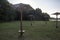 Wooden sunny umbrella with cobwebs on an abandoned beach with grass by the lake