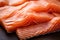 Wooden surface displays a close up of uncooked, succulent salmon fillets