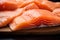 Wooden surface displays a close up of uncooked, succulent salmon fillets