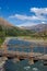 wooden suspension bridge held by ropes over river in valley