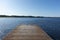 Wooden swimming dock pier with metal ladder on calm blue lake sunny day on nature finland