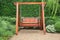 Wooden swing chair in natural green garden. Beautiful garden furniture