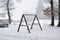 Wooden swing on a forest playground covered in snow in winter