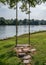 Wooden swing with rope hanging on tree at waterside