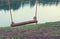 Wooden swing on a rope mount mounted on a tree on the shore of the lake.