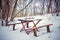 Wooden table and bench in the woods under the snow