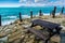 Wooden table and benches against the background of an emerald stormy sea. Mountains on the horizon.