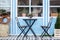 Wooden table and chairs on veranda of house. terrace with baskets and green plants