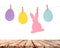 Wooden table and eggs and rabbits decoration garland on white wall. Easter holiday background