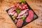 Wooden table filled with delicious cold meat selection. A plate with a variety of sausages with green vegetables green lettuce,