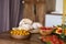 On wooden table is food, vegetables and bread are beautifully laid out,  knife sticks out of bread