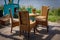 A wooden table and four wicker chairs - garden furniture standing on a bright wooden patio, on the riverbank.