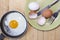 Wooden table with fried egg, eggshells, knife and fork