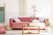 Wooden table in front of red sofa in pastel living room interior