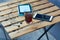 Wooden table with glass of black strong coffee and mobile headphones, smartphone and e-book. Work and study in cafe.