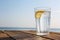 Wooden table with glass of refreshing lemon drink on hot summer day outdoors