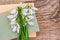 On a wooden table with old books lies a bouquet of white snowdrops with copy space